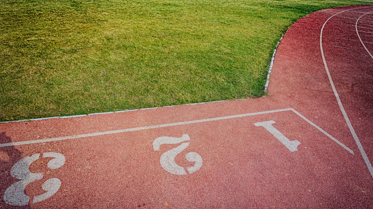services-01 A bird's-eye view of a vibrant outdoor running track and lush green sports field.
