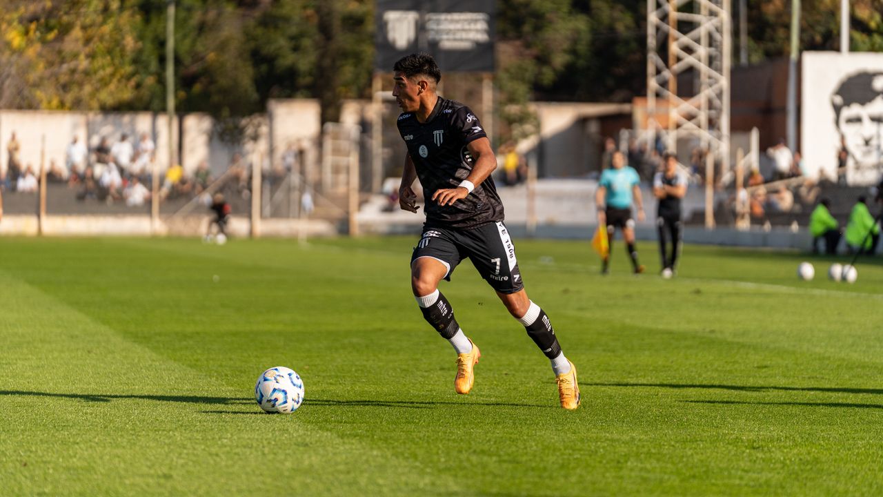 Soccer player dribbling the ball during a daytime match outdoors.
