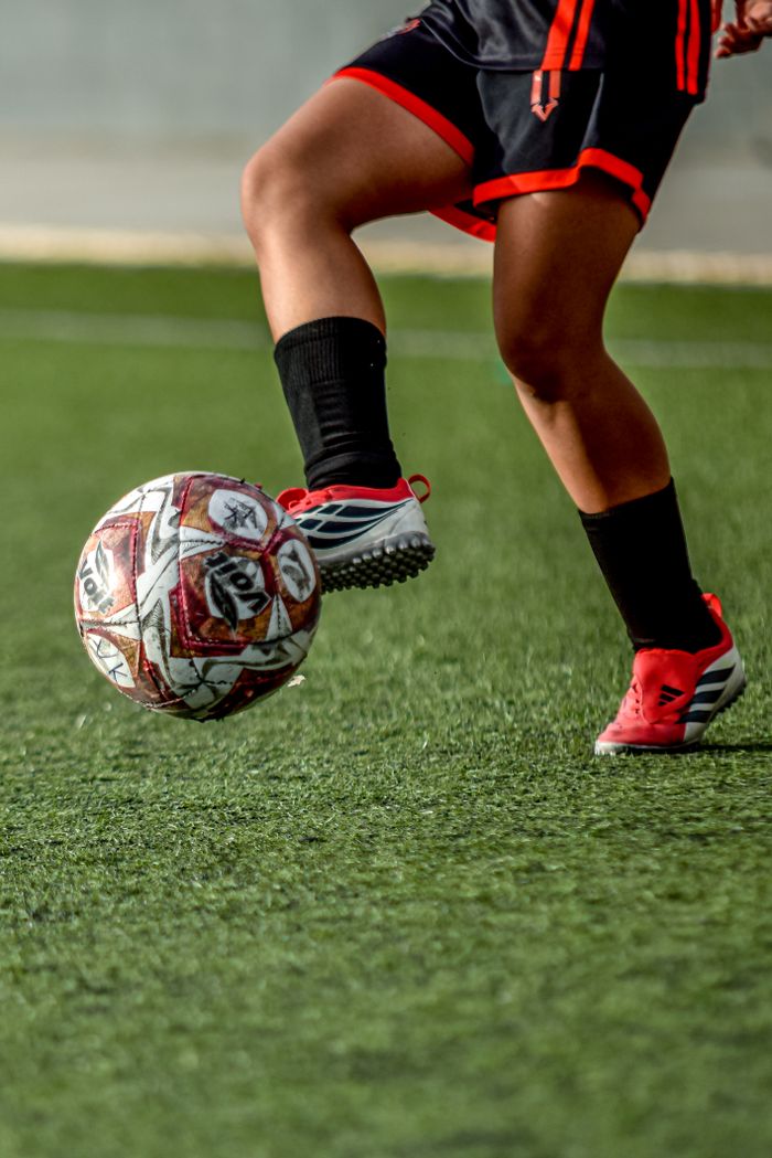 gallery-03 Close-up of a soccer player skillfully controlling a ball on a field.